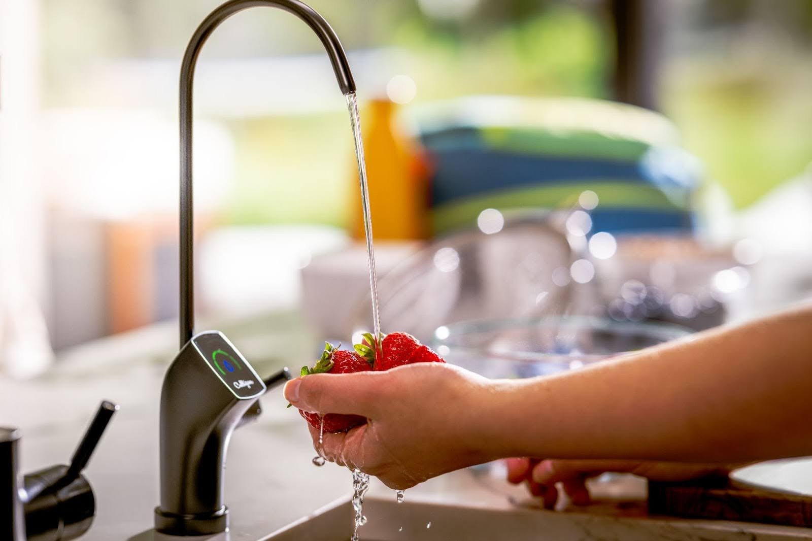 Person washing strawberries in kitchen sink